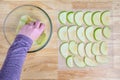 WomanÃ¢â¬â¢s hands taking granny smith apple slices out of a glass bowl and laying them out on a mesh tray for dehydrating Royalty Free Stock Photo